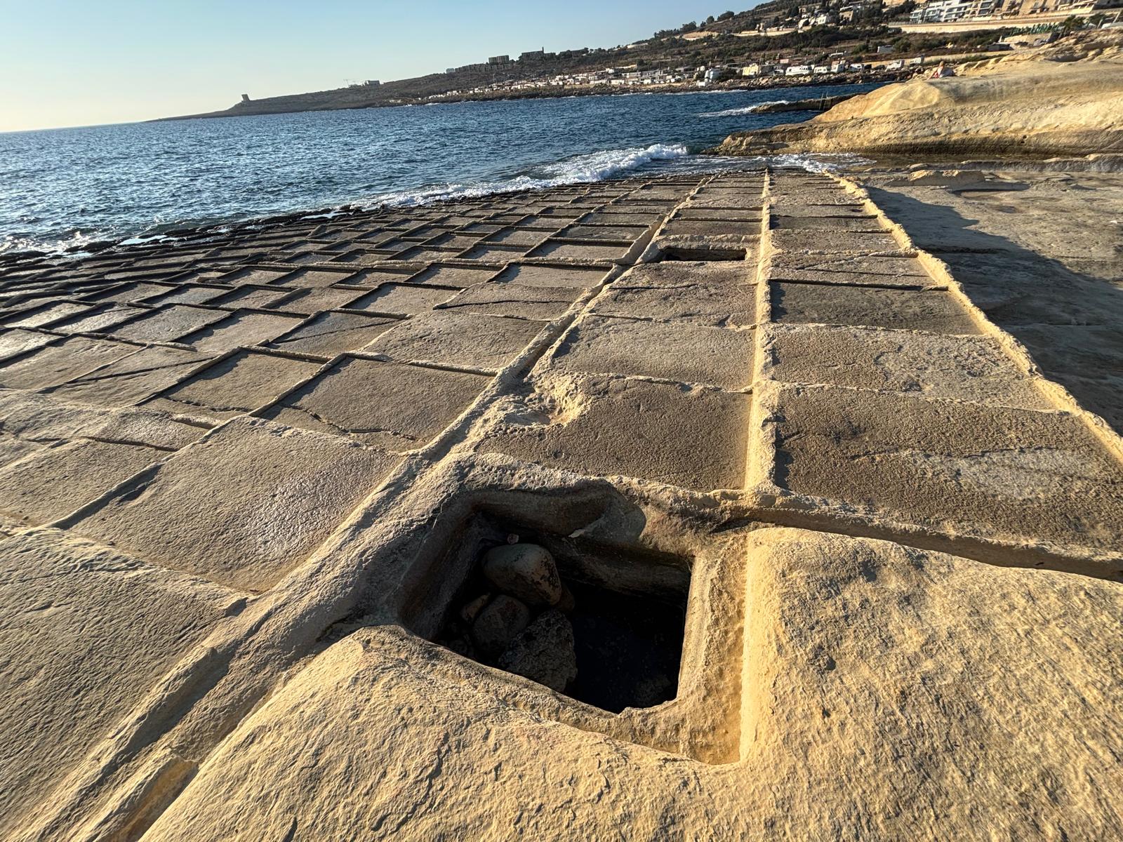 Panoramic view of the Baħar iċ-Ċagħaq salt pans stretching toward the horizon under bright sunlight