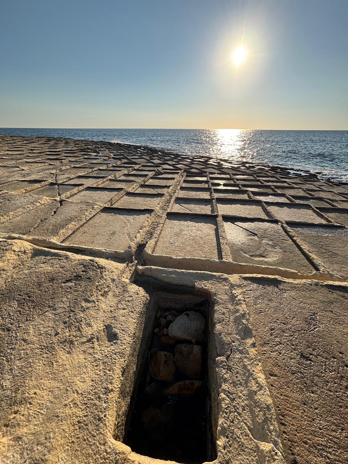 Angled profile view of the lower crystallizing pan grid framing the open Mediterranean coast