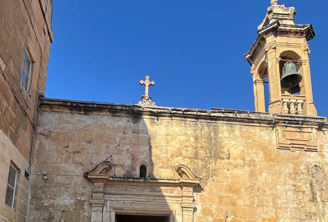 Detailed close up of the pediment stone cross with a carved skull memento mori symbol at the top of the Tal-Ftajjar chapel in Luqa