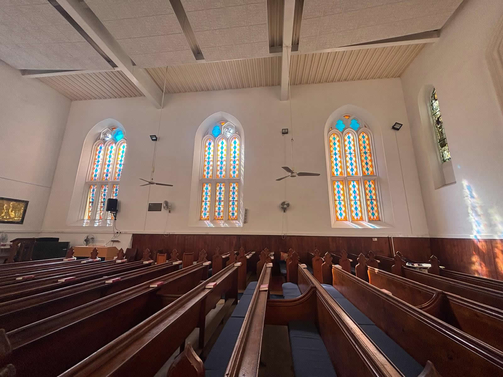 Interior of St Andrew’s Scots Church Valletta showing the  wooden pews and large stained glass windows