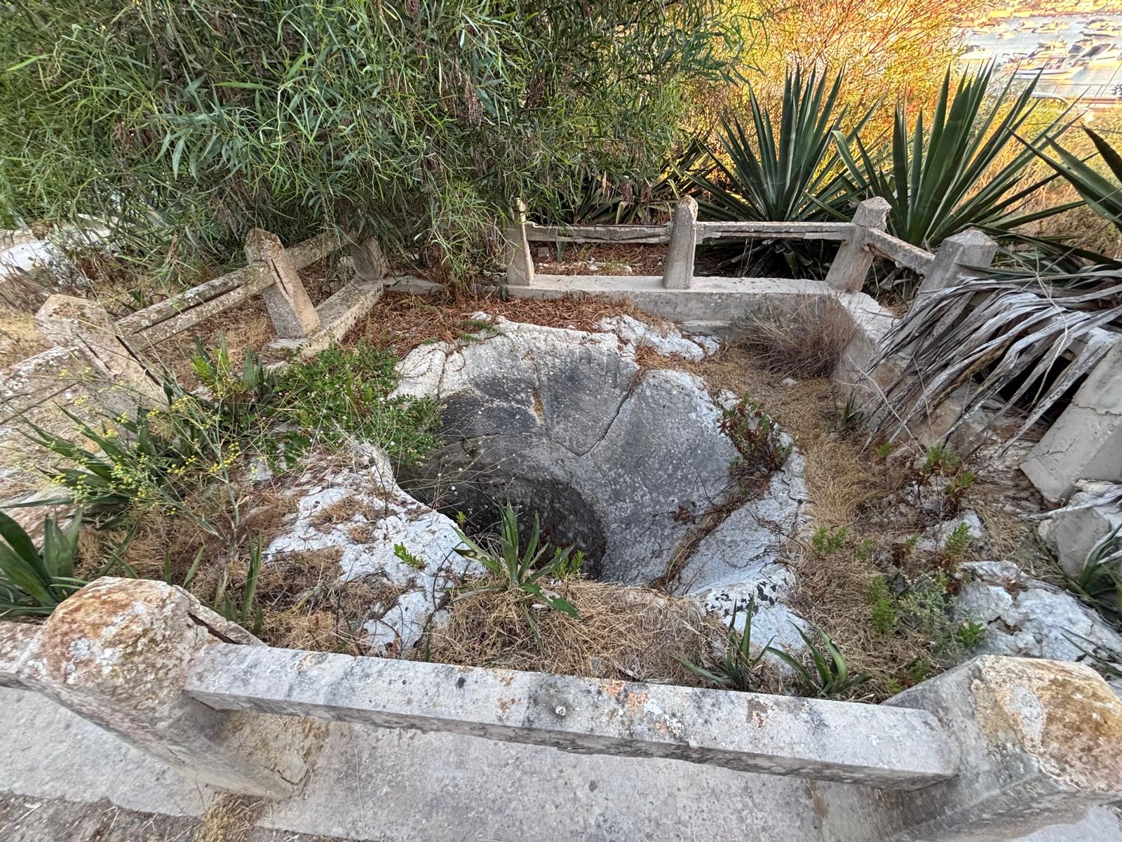 Overhead view of the rock-cut exterior Fougasse at Salini inside its protective fence boundary