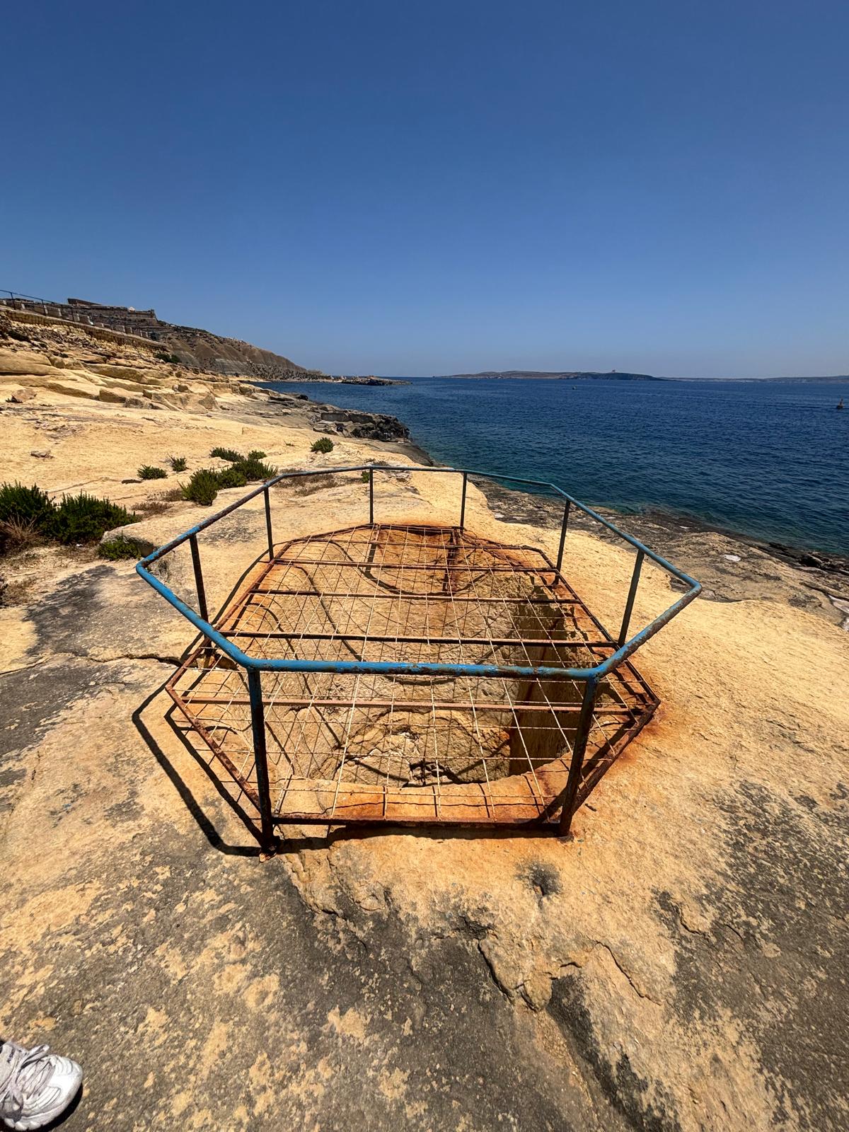 Wide angle perspective showing the protected fougasse on the yellow limestone shore platform looking towards the blue sea channel