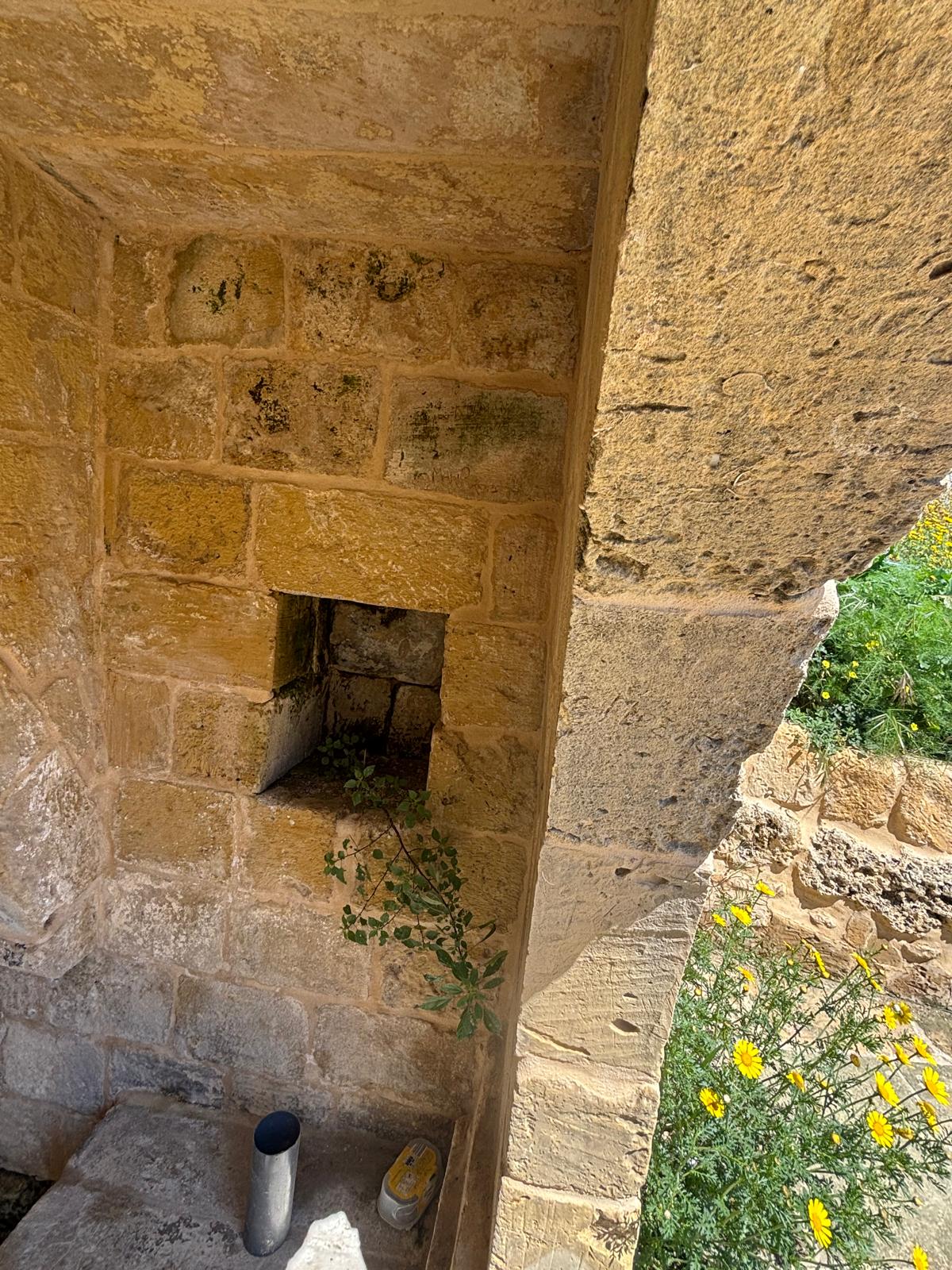 Close up detail of a square storage niche cut into the interior limestone wall of the wash house