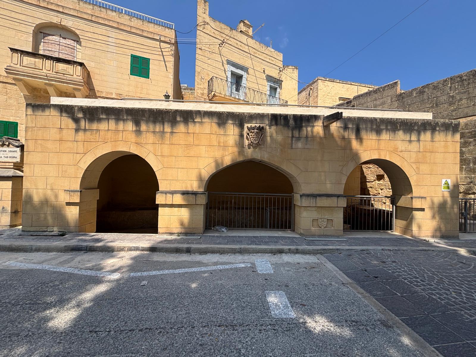 Straight-on wide view of the three stone arches forming the facade of the Għajn tal-Ħasselin wash house