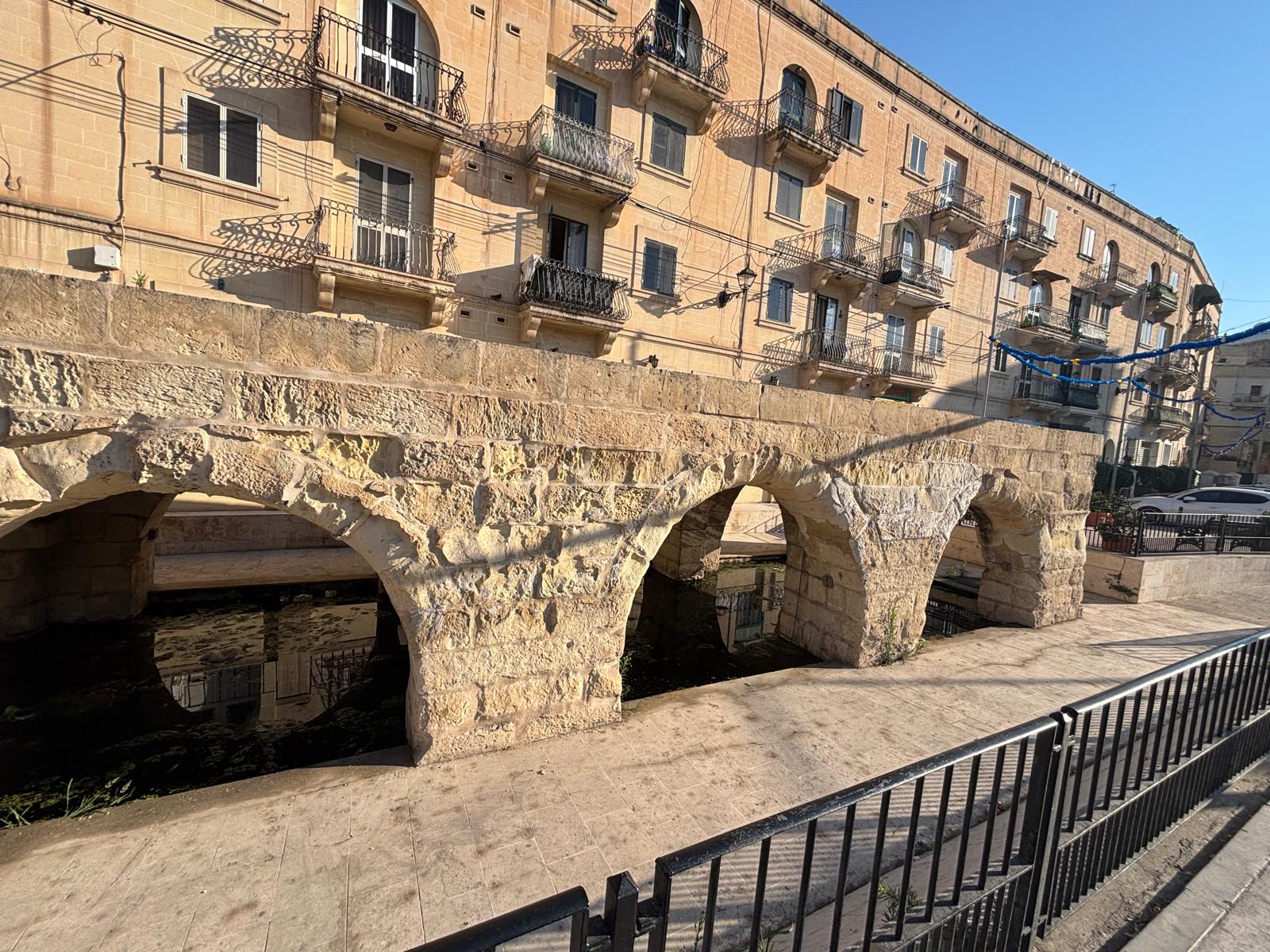 Close up view of the thick textured limestone block arches of Ghajn tal-Wied wash house in Msida