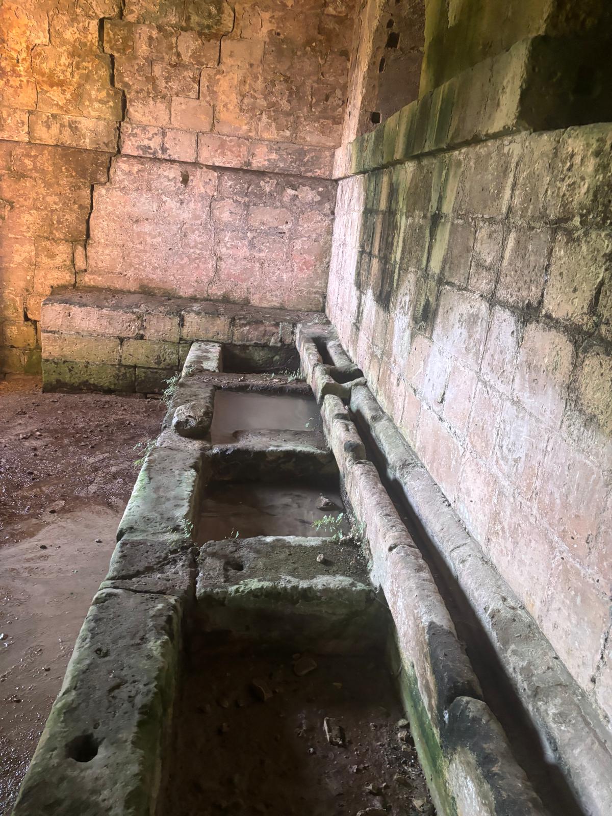 Axis view of a long row of continuous stone washbasins with water channels inside Ghajn Hammiem Rabat