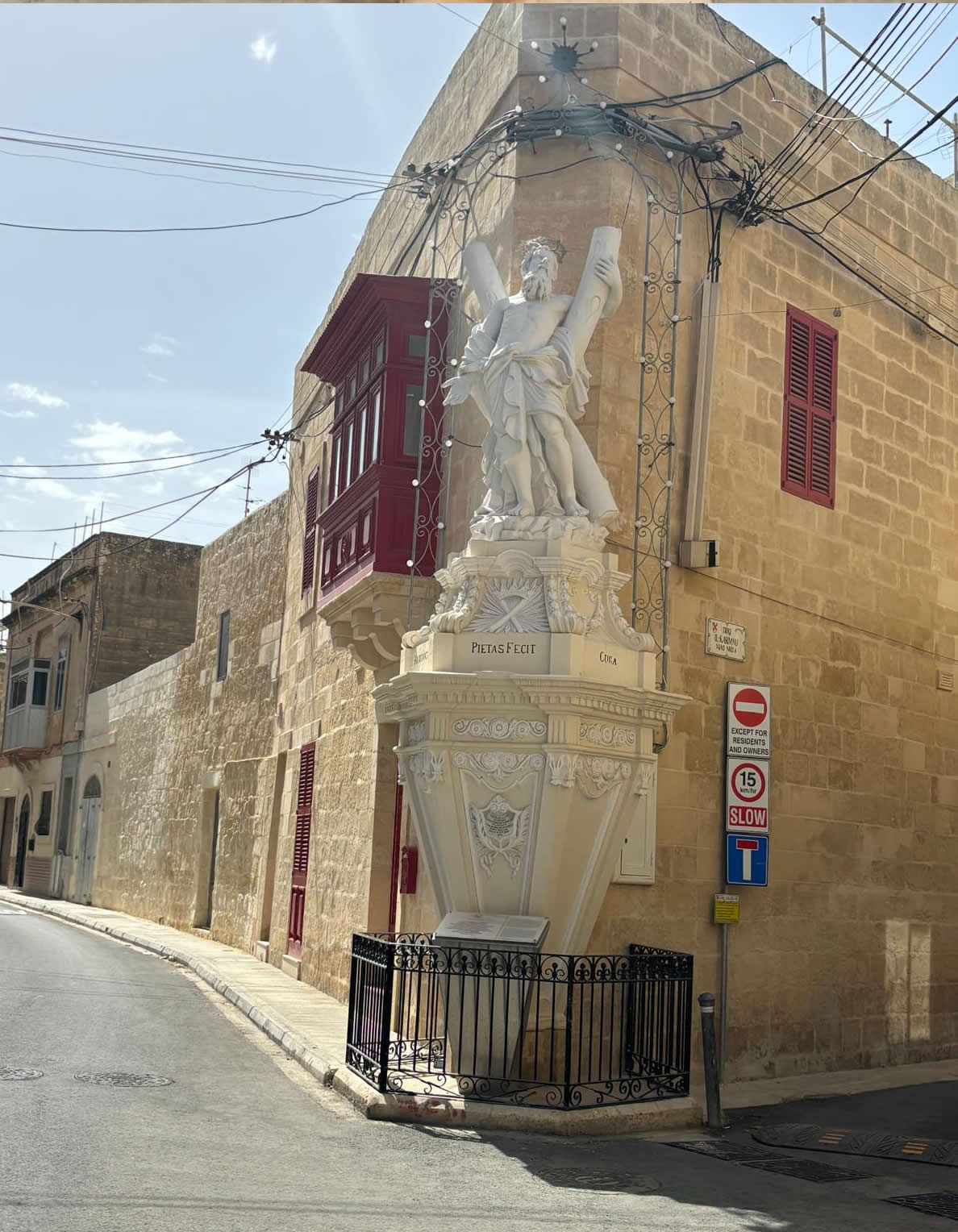 Large stone statue of St Andrew on a high decorated pedestal with the inscription Pietas Fecit at the corner of Triq il-Karmnu in Luqa Malta