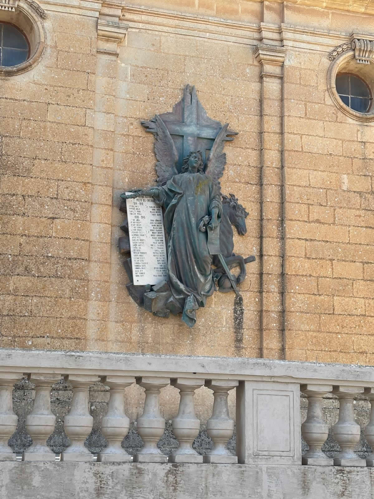Nadur War Memorial in Gozo showing the angel, cross, horse and Roll of Honour beside the parish church